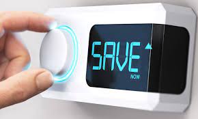 Spartipps gegen die hohen Strompreise in Österreich, Hand dreht am Regler eines an der Wand befestigten Thermostats. Auf dem Display des Thermostats steht Save.